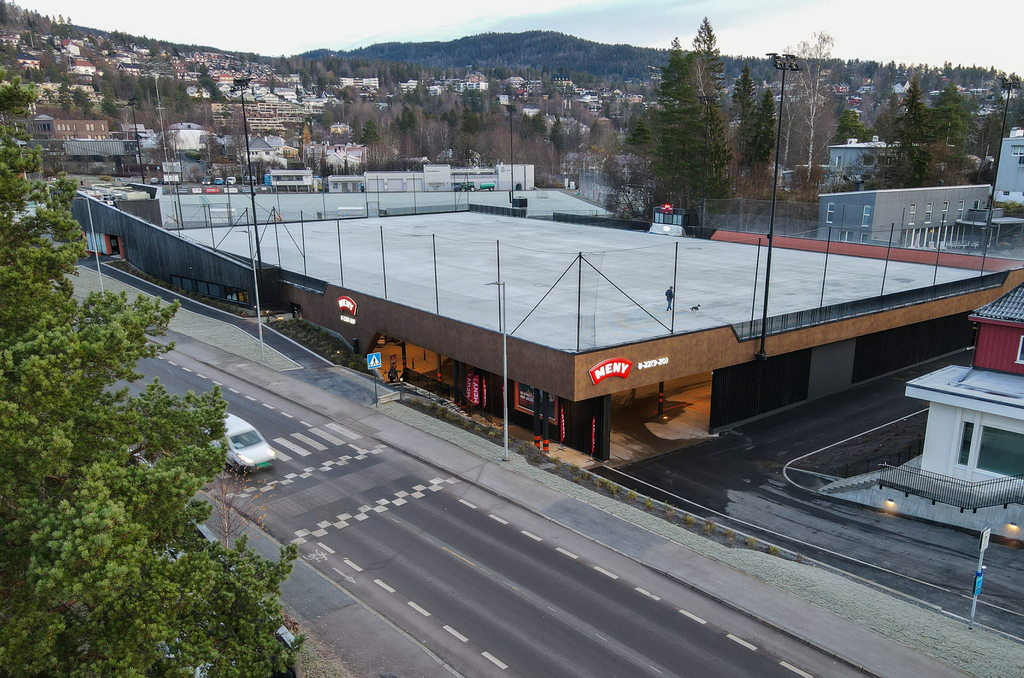 Bilde av anlegget, tatt ovenfra. Viser Meny-butikken som ligger ved siden av en bilvei, og over butikken ligger isflaten. 