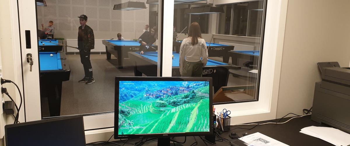 PC på pult, med vindu til biljardhallen