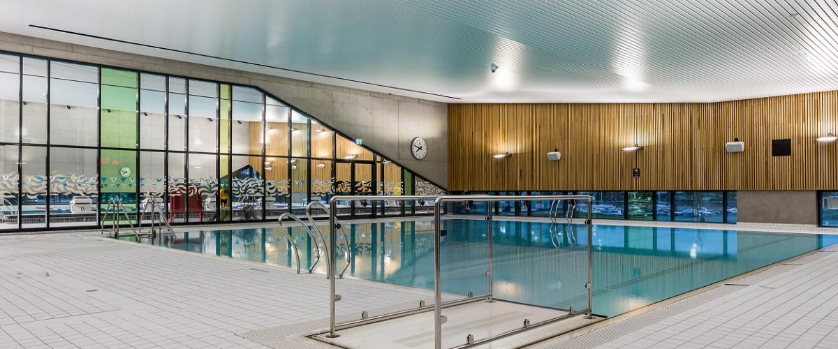 Innsiden av svømmehallen med fliser, basseng og vinduer. 