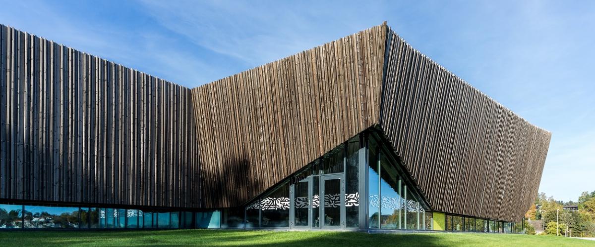 Utsiden av bygg med vindusfronter og treverk i overkant.