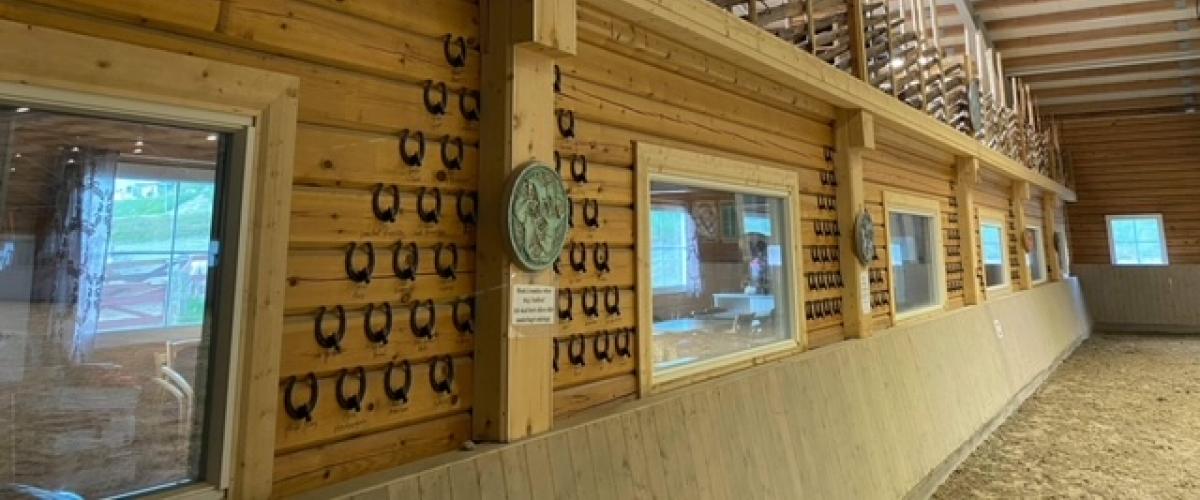 Klubbhus sett fra ridebane. På veggen er det hestesko, og over klubbhuset er det satt en skigard som gjerde for tribune