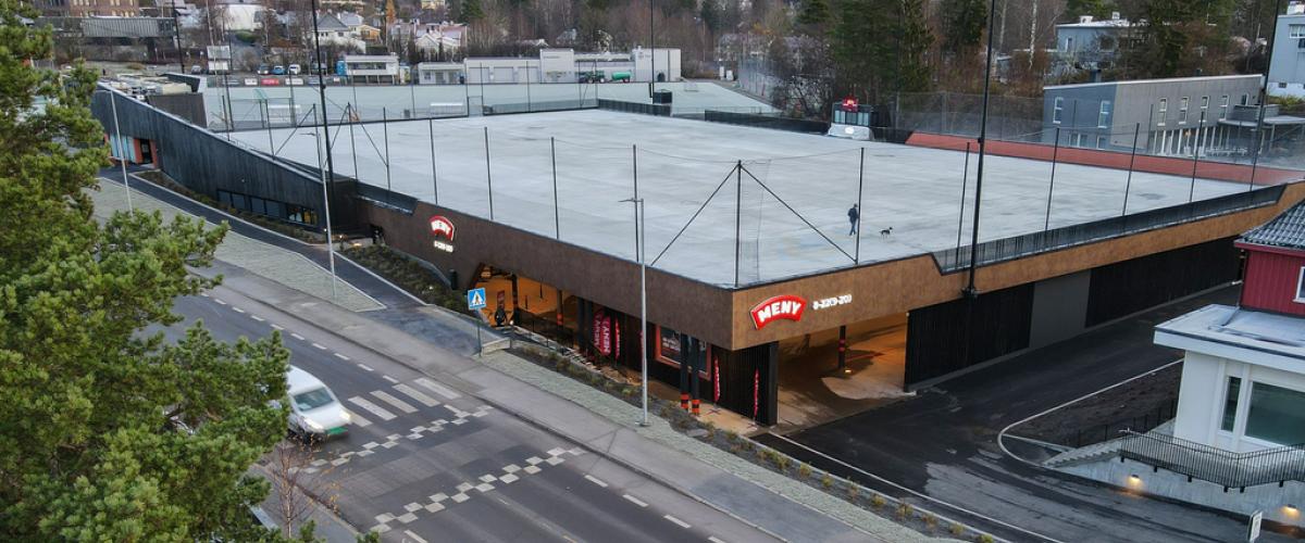 Bilde av anlegget, tatt ovenfra. Viser Meny-butikken som ligger ved siden av en bilvei, og over butikken ligger isflaten. 