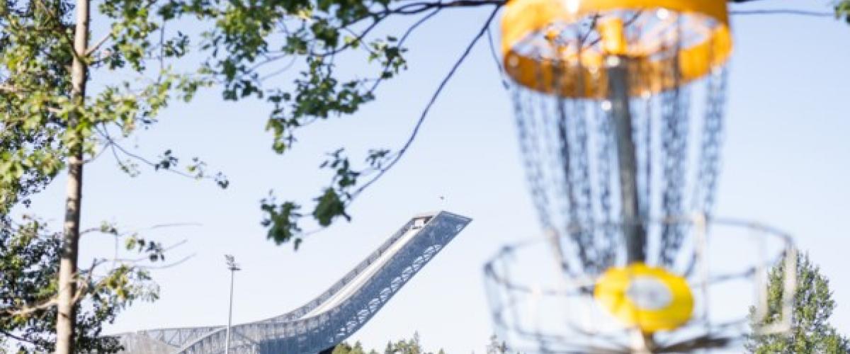 Kurvene er plassert i hele anlegget, deriblant ved den ikoniske hoppbakken. Foto: Skiforeningen Bilde av en frisbeekurv og hopbakken