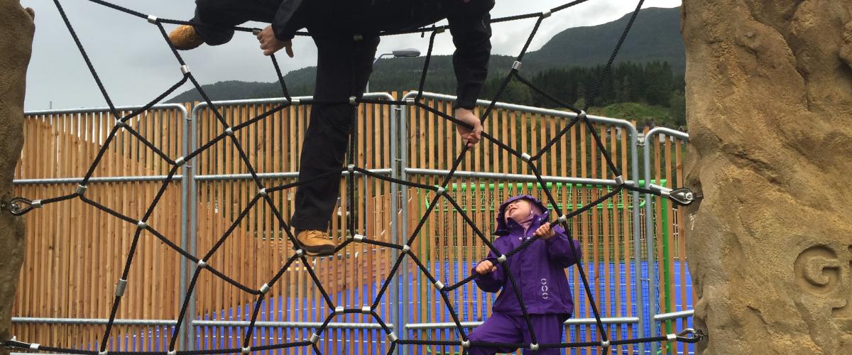 Barn med voksen som klatrer i eit nett