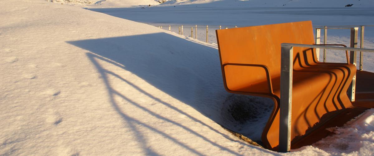 Cortenstålbenk i snødekt landskap