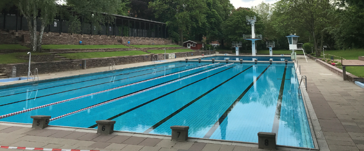 Utendørs svømmebasseng, med hoppetårn og grøntområder.