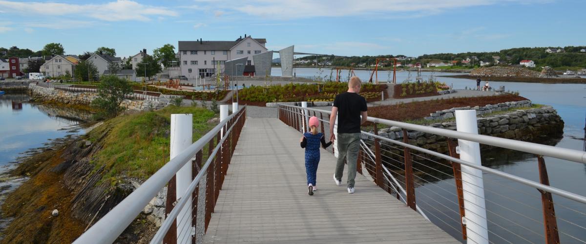 Gangbro over fjorden til halvøy med park og klatreseil