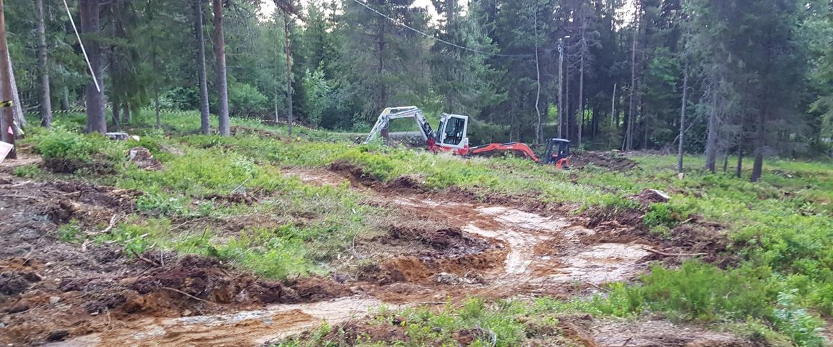 Gravmaskiner som bygger løype i skogen
