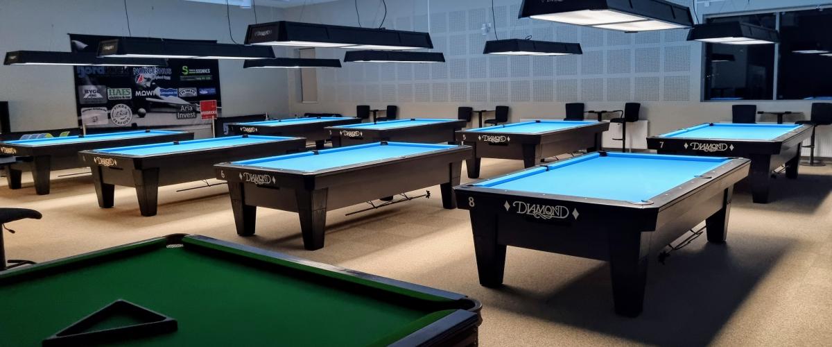 Åtte biljardbord i et åpent rom med vinduer i Hyllestadhallen