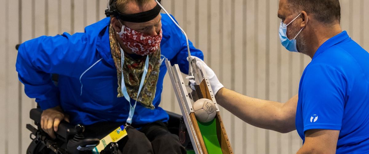 Landslagsspiller får hjelp til å plassere ballen på en bocciarenne.