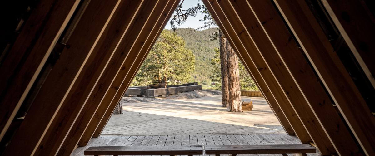 Utsyn fra inni en gapahuk ut på en platting og grillplass