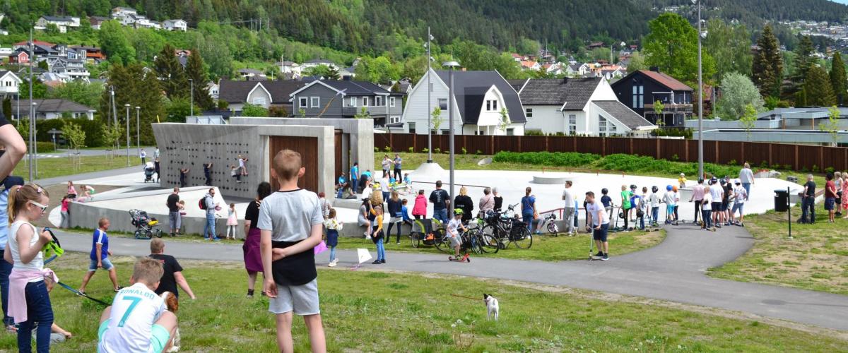 Mange mennesker i alle aldre som ser på skate-, BMX- og sparkesykkelanlegget.