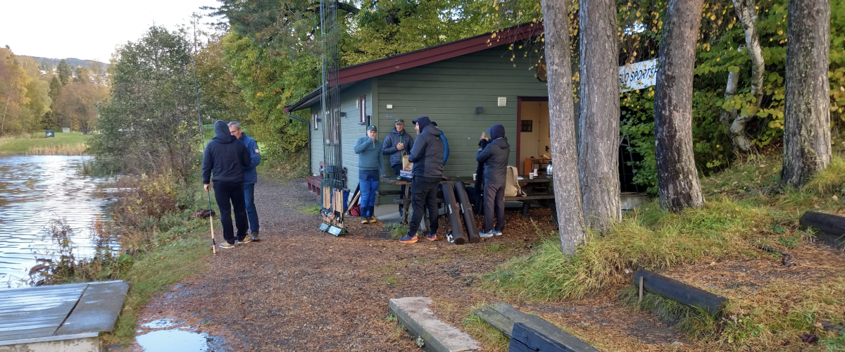 Bilde av anleggets klubbhus med en rekke fiskere som oppholder seg utendørs