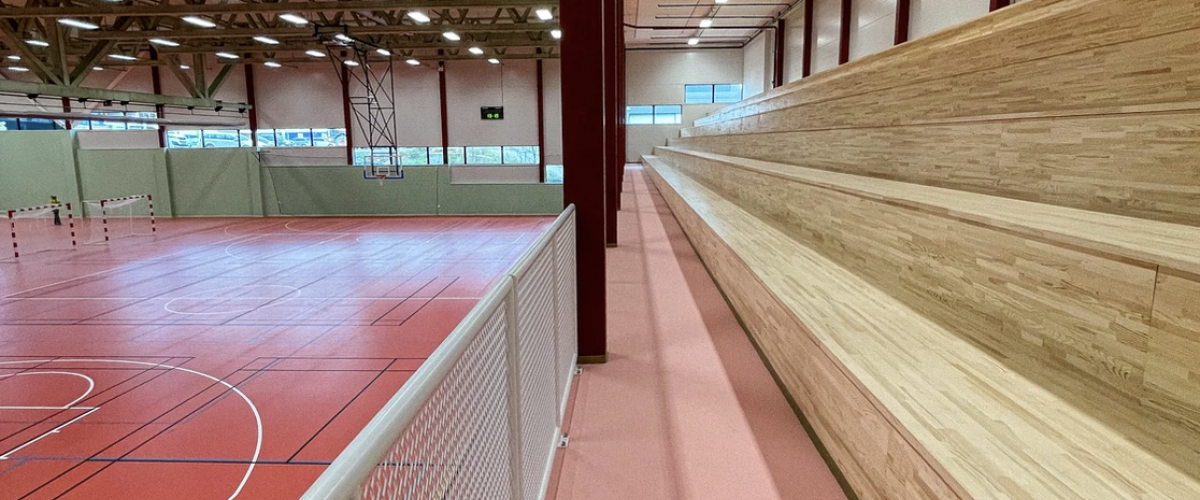 Bilde som viser tribunen i ThonHallen, der denne er lokalisert på den ene lanhgsiden i hallen, og laget av treverk. 