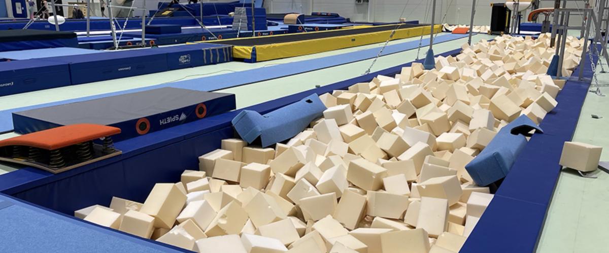 Bildet viser turnutstyr i en treningshall på Åsane Arena, inkludert skumgrop og apparater for forskjellige øvelser.