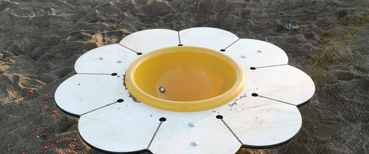 Vannbord utformet som en blomst plassert i sandkasse