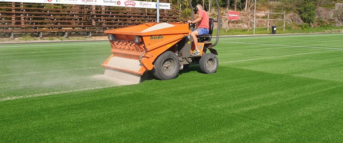Vedlikehold av banen med maskin som strør sand