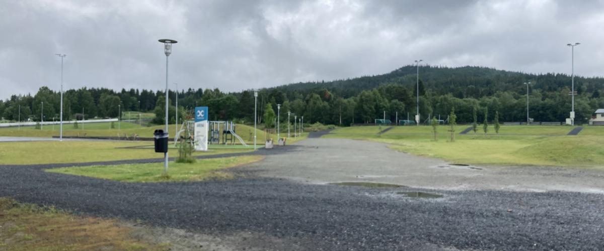 Inngangsparti til Arenaen. Belyst med lyktestolper og gruslagt vei mellom aktivitetsmomenter på arenaen.