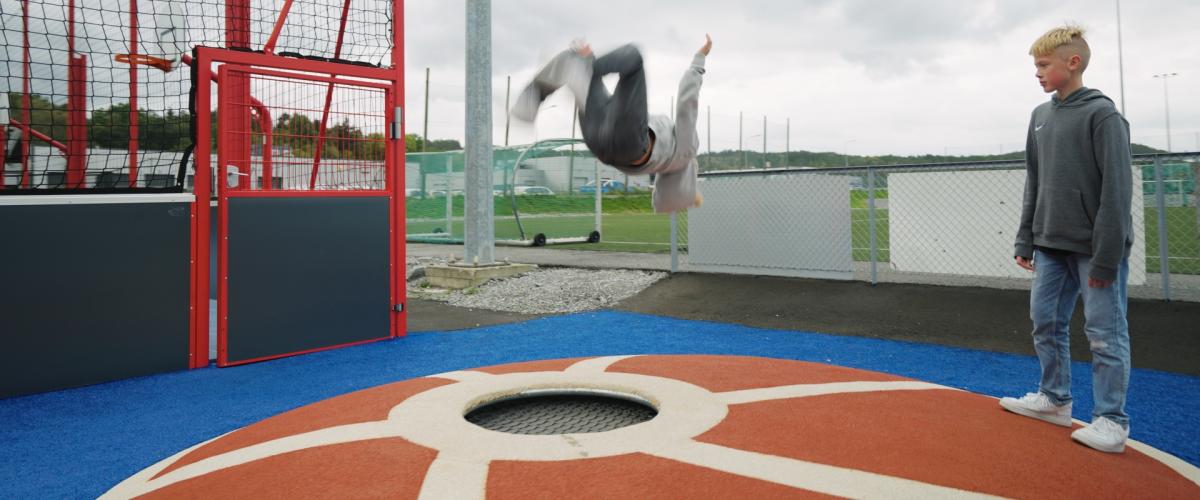 Gutt som gjør triks på liten trampoline
