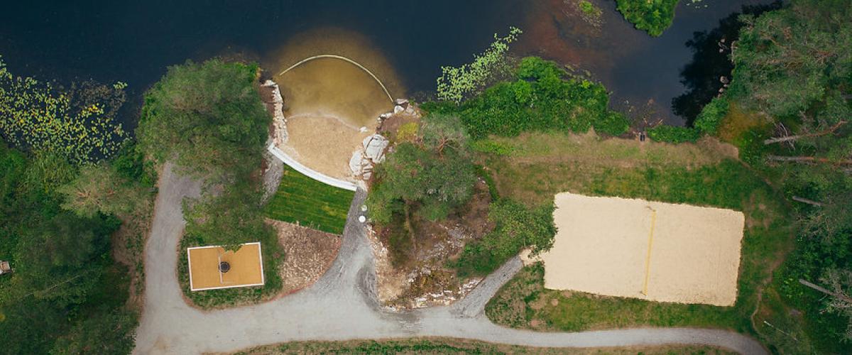 Sandvolleyball og badestrand er det også gjort plass til, som en del av satsningen på besøk også i sommerhalvåret. Foto: VSA Sandvolleyballbane og en liten sandstrand sett ovenfra