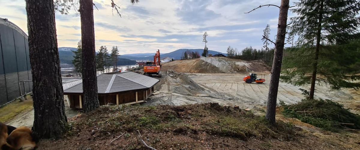 Veivals og gravemaskin i arbeid med å gjøre klar tomt i forgrunnen er gapahuken.