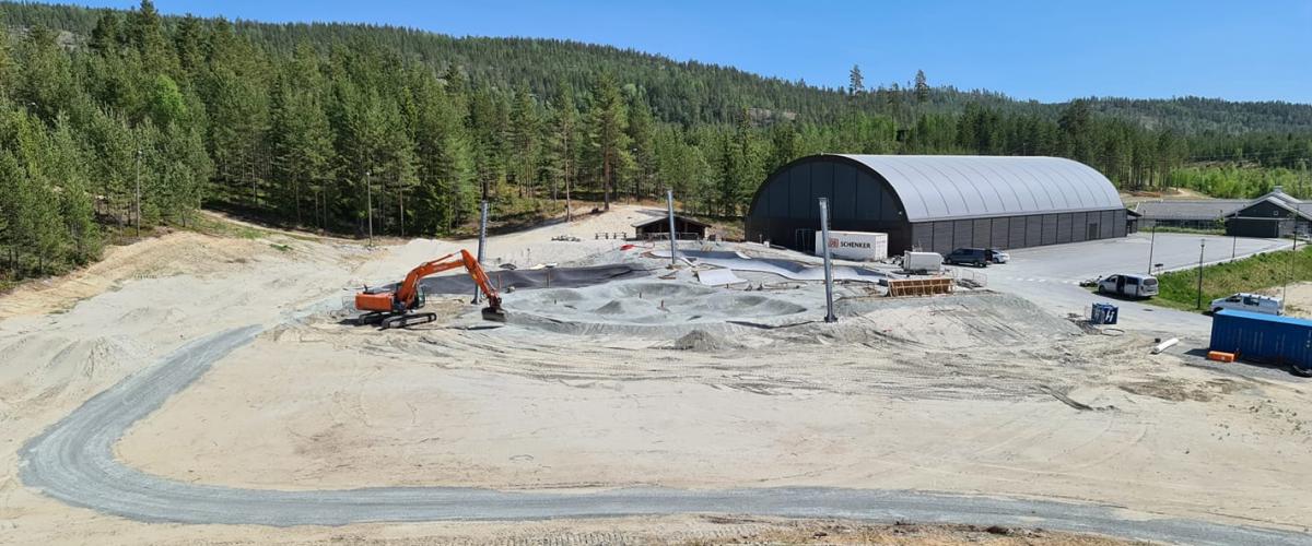 Gravemaskin er i full gang med å planere tomta