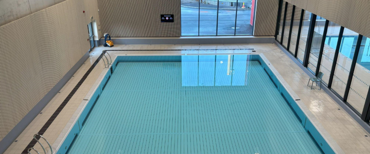 Bildet viser et nytt oversiktsbilde av et av de mindre bassengene med samme vindu i bakgrunnen. Glassvegger inn til selve svømmehallen. 