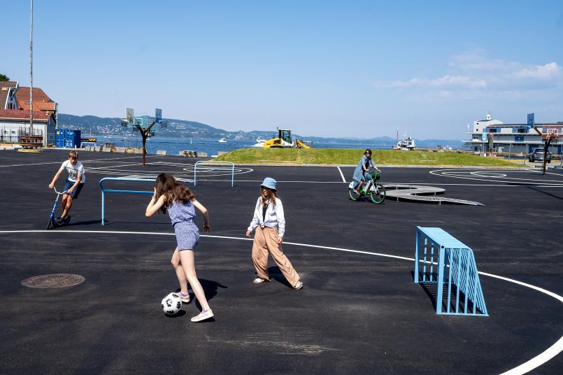 Barn som spiller fotball og noen som sykler på pumptrack i bakgrunnen 
