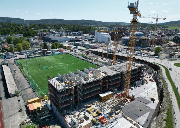 Blokker og tårnkraner foran kunstgressbane