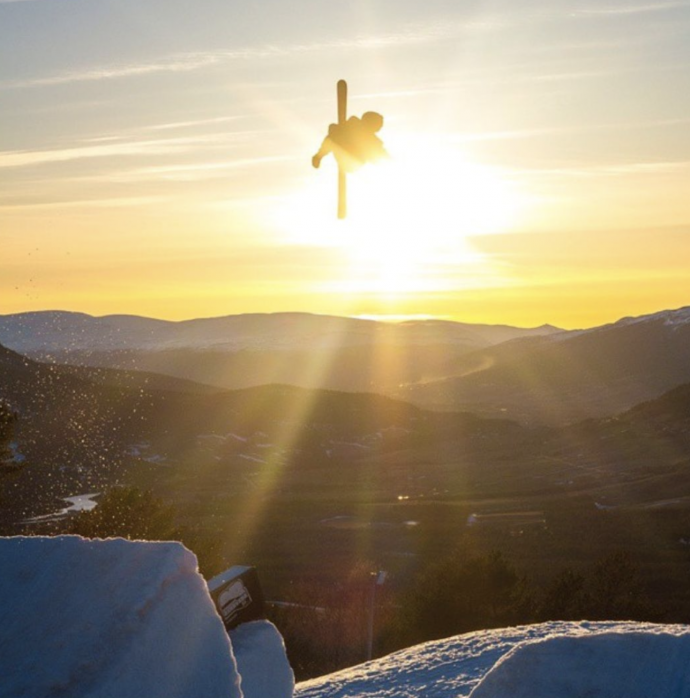 Bilde av enn skikjører som hopper på et av anleggets "Big Jumps" i solnedgang. 