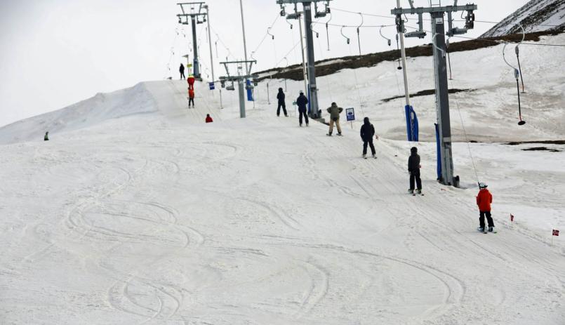 Bilde av den nye skibakken som har åpnet på svalbard, der man på høyre side ser skiheisen med en rekke barn og unge i