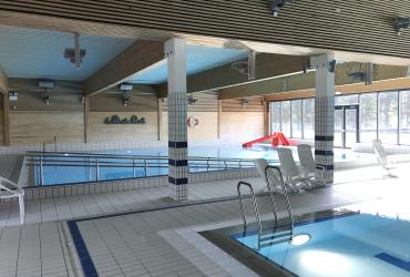 Innandørs symjehall på Tinfos bad med basseng, trepanel og store vindauge mot uteområdet.